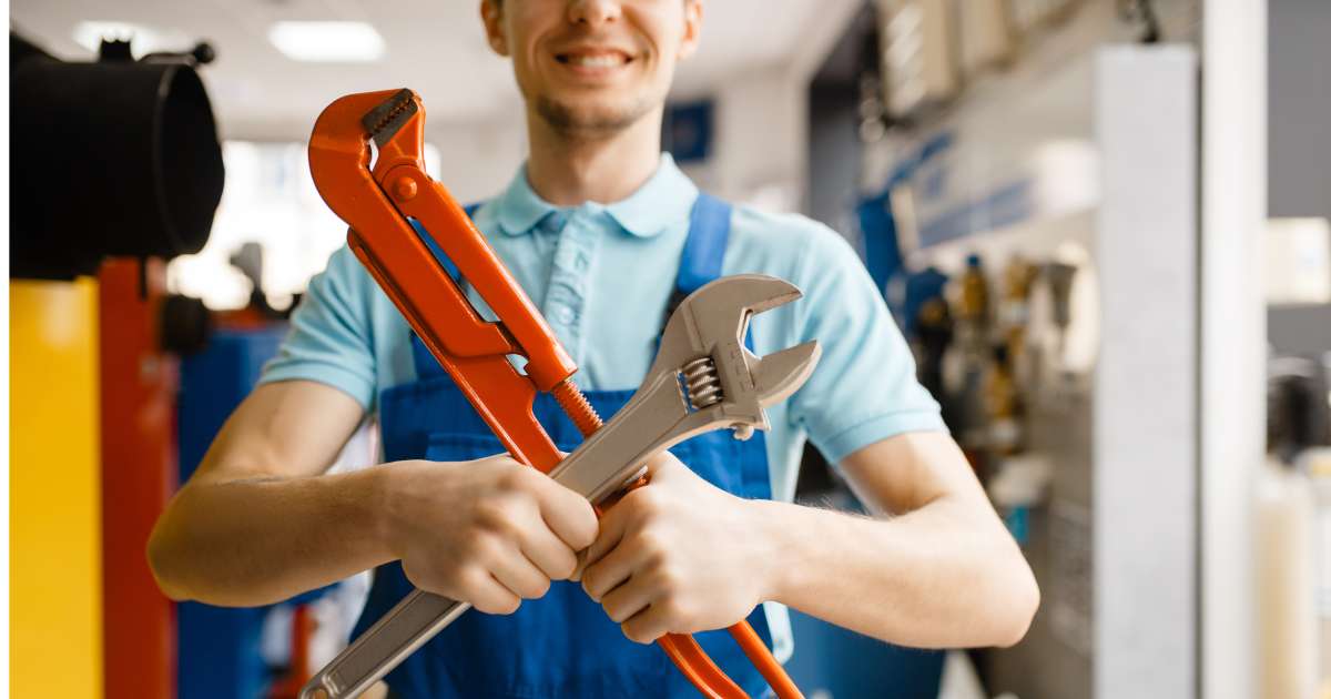 Plumber poses with pipe wrenches, plumbering store