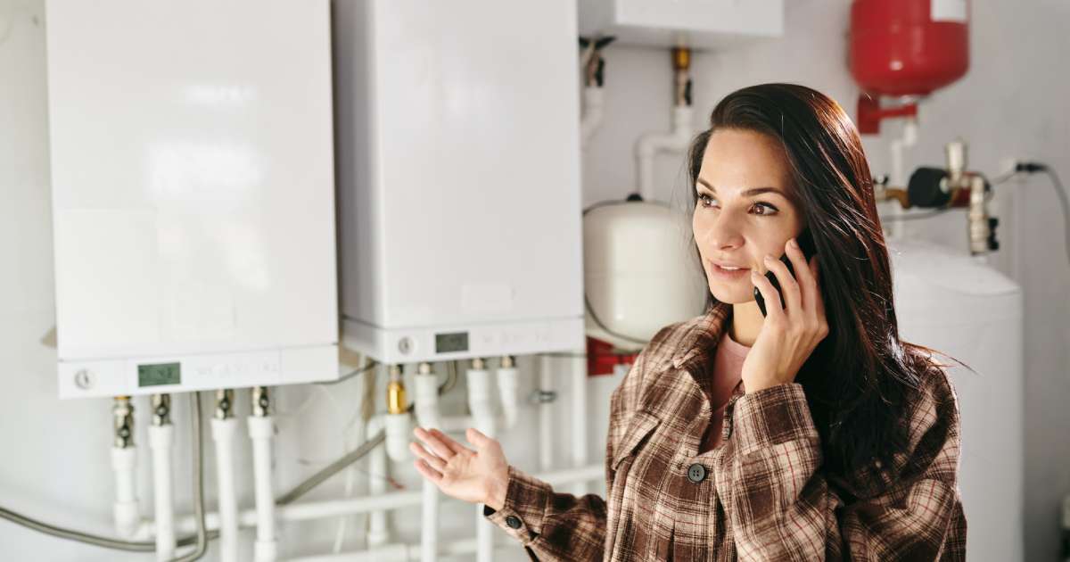 Young woman holding smartphone by ear while calling plumber
